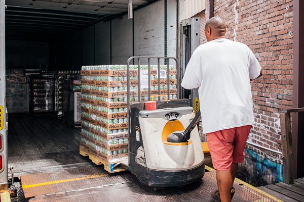 man loading packaged beer into truck for distribution 1200x628 1