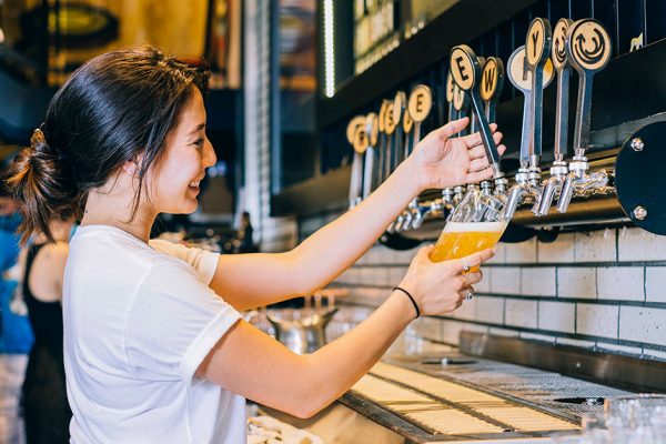 woman pouring draught beer in taproom x
